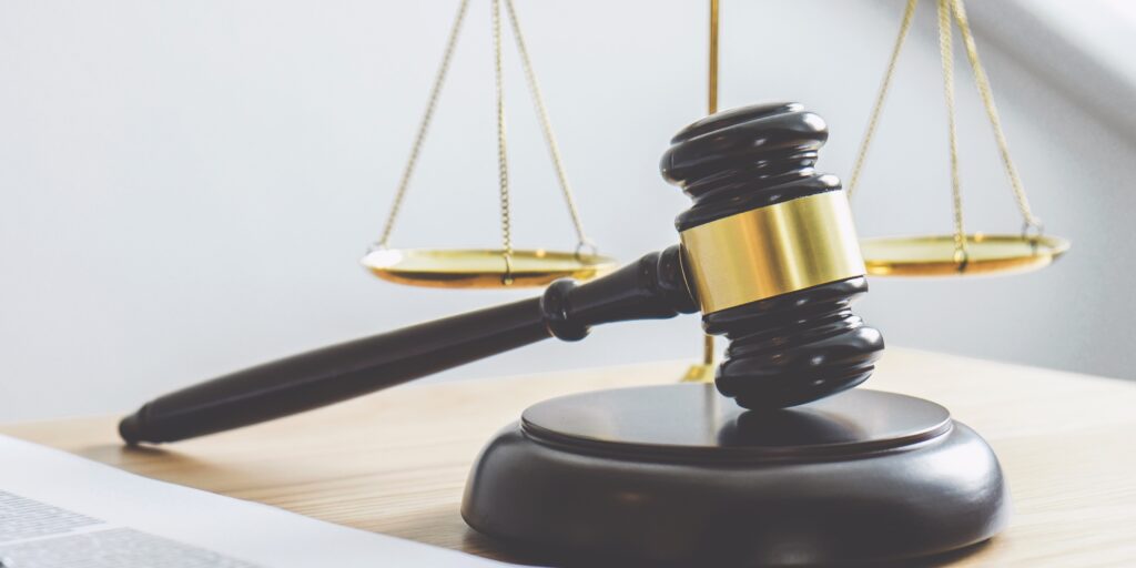 Close-up of a judge’s gavel and balanced scales on a desk, symbolising legal penalties and regulatory enforcement.