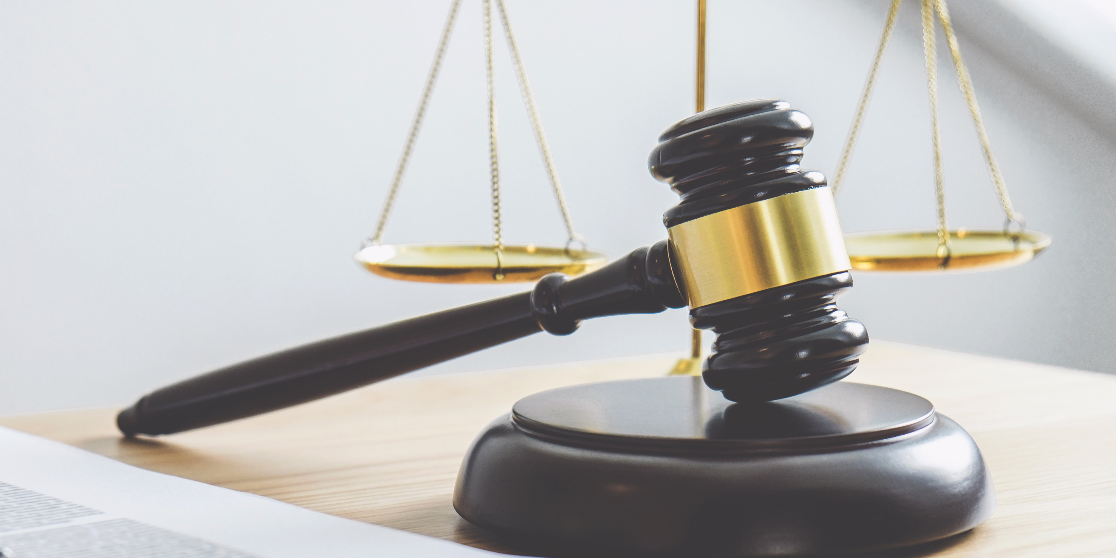 Close-up of a judge’s gavel and balanced scales on a desk, symbolising legal penalties and regulatory enforcement.