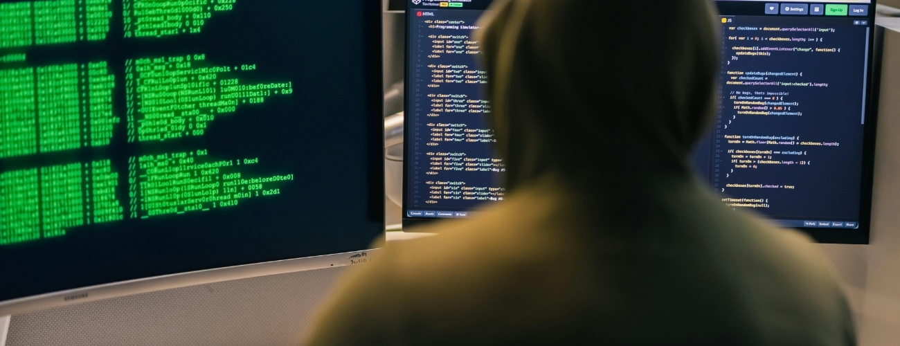 Person monitoring computer screens displaying cyber security code and AI-powered cyber threats
